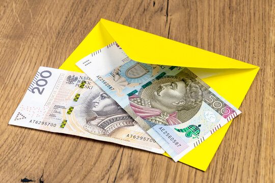 Polish banknotes in yellow envelope on wooden background