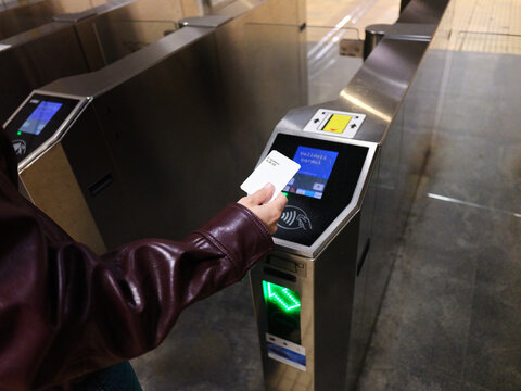 Person validating public transport card at Bucharest metro turnstile