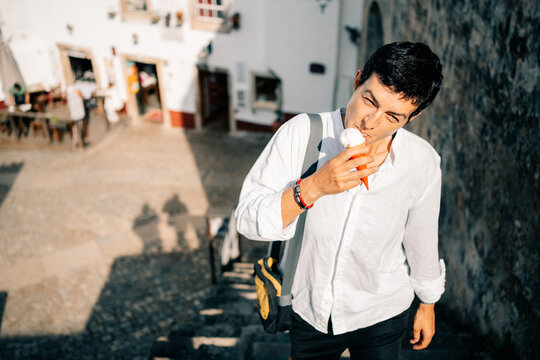 Person Enjoys Ice Cream While Walking Down Steps in a Town