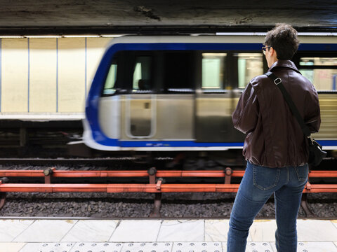 Passenger observing passing metro train in Bucharest subway station