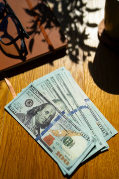 Dollars on a wooden table in bright sunlight