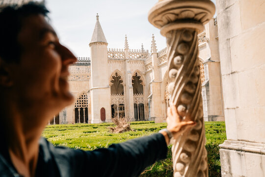 Person Touches a Stone Pillar Near a Historic Building