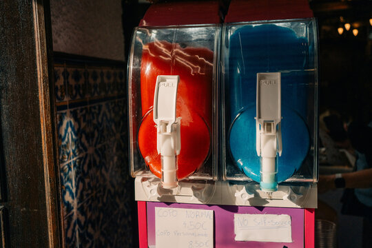 Fruit Ice Machine With Red and Blue Dispensers Indoors in a Cafe