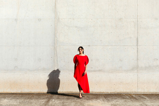 Woman in red dress against concrete wall