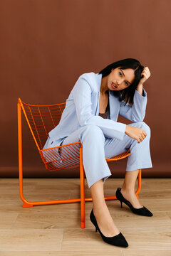Woman posing in blue suit on orange chair