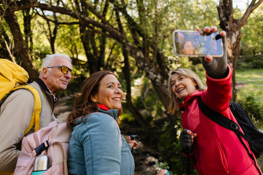 Senior friends enjoying nature taking selfie during hiking trip