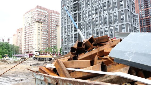 Construction demolition debris and scrap wood and metal materials at urban building site with residential buildings in background