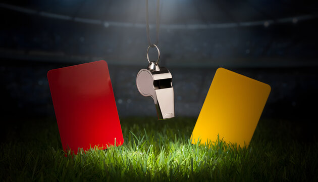 A silver referee whistle hanging on a cord between a red card and a yellow card on stadium grass under a dramatic spotlight at night, conceptualizing sports discipline and rules.