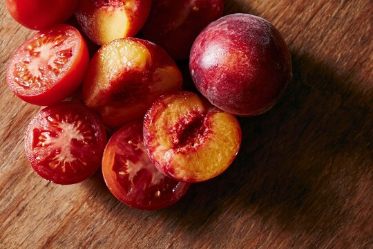 Overhead flat lay of sliced peaches and whole peaches arranged on a wooden surface, showcasing vibrant colors and textures of the fruit