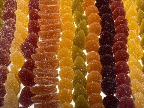 Vibrant rows of assorted sugar-coated gummy candies in warm gradient tones