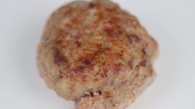 Savory meat patty. Crispy homemade meatball on plate. Goldenbrown seared meat patty with rustic texture. Closeup of crispy homemade cutlet with grainy crust on white background
