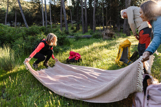 Group preparing picnic blanket on a sunny morning