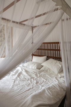 A luxurious unmade bed with canopy