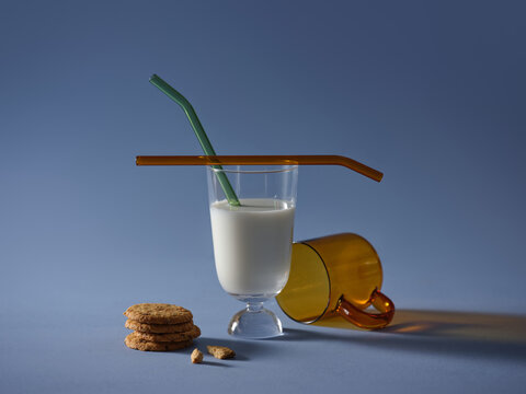 Milk and cookies with colorful straws on a blue background