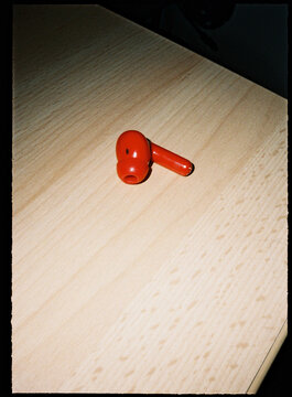 Red wireless earbud lying on timber surface