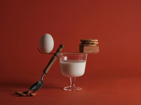 Balanced breakfast concept with egg, cookies, milk, and almonds on red