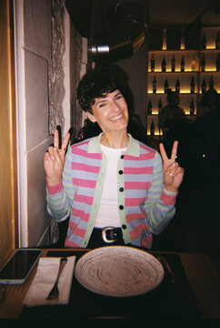 Young woman smiling showing peace sign in restaurant