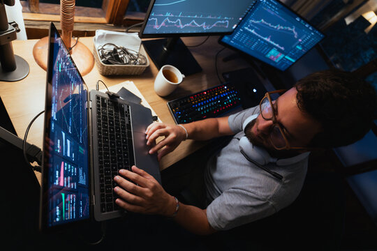 Man trading and Analyzing Stock Charts on Multiple Screens at Night