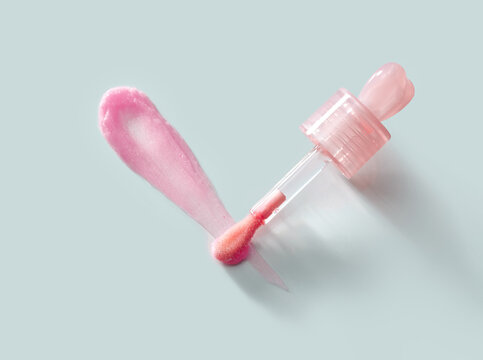 Lip gloss application with a dropper on a light gray background.