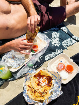 Man Eating Molletes on Sandy Beach 