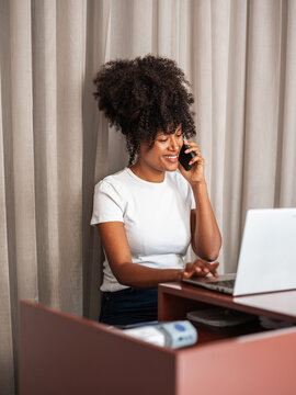 Woman Talking On Phone While Working On Laptop At The Retail Shop