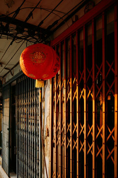 Red lantern hangs outside closed shops in evening light