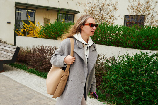 Woman walks on the street with a bag while wearing sunglasses 