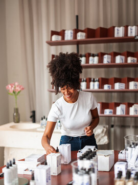 Smiling Woman Arranging Skincare Products in Cosmetics Shop