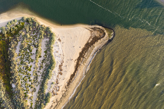 Coastal river mouth flowing past a sandy point with hardy vegetation