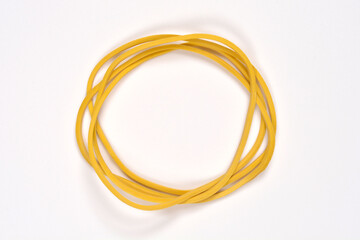Naklejka premium A top down shot shows a small bunch of yellow rubber bands tangled together into a circular shape on a plain white background.