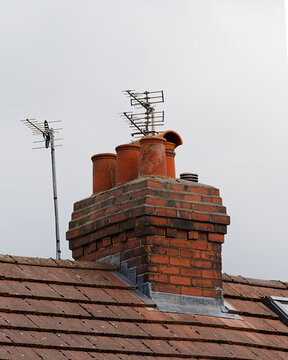 Brick chimney stack with terracotta pots and tv aerials