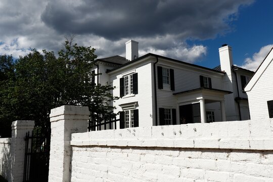 White brick wall surrounds front of mansion