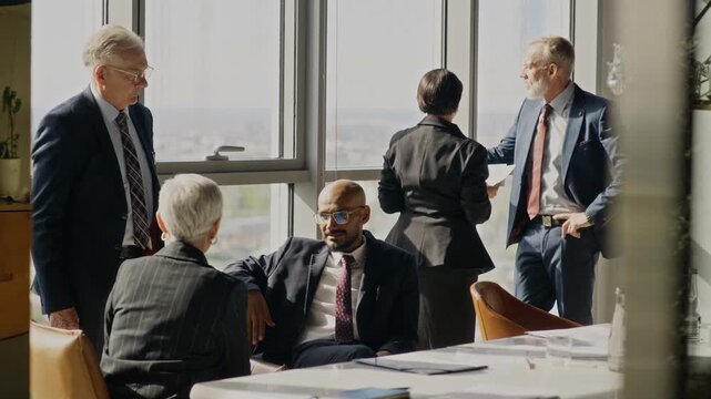 Medium long shot of diverse business executives discussing strategy during corporate meeting. Video suits corporate communication campaigns