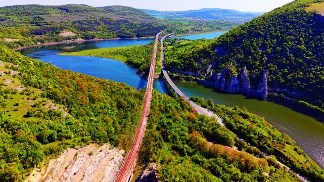 Landscape with bridges and rock formations, Bulgaria. Elevated view of parallel spans traversing reservoir flanked by limestone pillars and dense vegetation under clear sky.