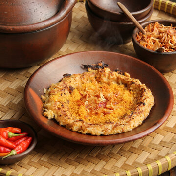 Hot Steaming Kerak Telor, Indonesian Traditional Spicy Omelette on Clay Plate, Jakarta Street Food with Fried Shallots and Serundeng, High Angle View on Woven Bamboo Tray, Food Photo