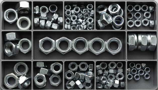 Assorted metal hex nuts organized in compartment storage box