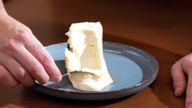 Slow motion close up of scraping creamy texture of San Sebastian cheesecake with a spoon.