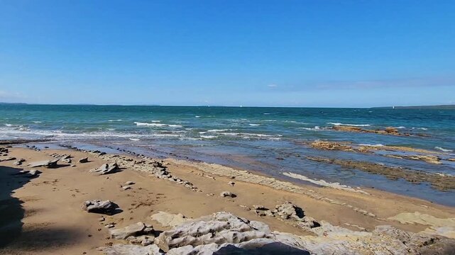 Auckland, New Zealand - Baywater rocky shoreline tidal pools turquoise ocean waves coastal landscape sunny day scenic waterfront nature video. Ideal for travel, nature and landscape stock use.