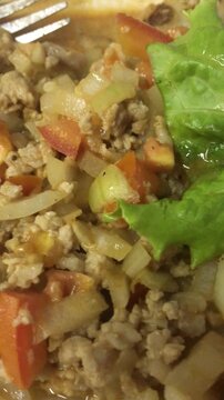 Close-up of Thai Sweet Basil, Tomato and Pork on a White Plate Portrait Aspect