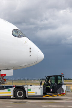 Modern widebody big long haul jet aircraft towed by ground vehicle on airport taxiway tarmac under sunlight. Engine cockpit crew performs technical operations before next scheduled flight airport