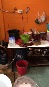 A panning shot of the cooking area of a Thai restaurant in Bangkok showing various utensils, cookware and ingredients. 