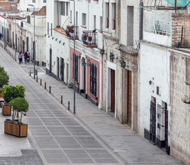 Obraz premium Cusco, Peru, March 12, 2026: Quiet historic street with colonial buildings and stone facades in the old town of Cusco. Urban view of traditional architecture in the Peruvian Andes.