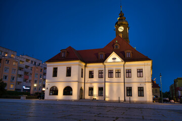 Fototapeta premium Historic Town Hall With Clock Tower Over Quiet Urban Square At Sunset - City Of Lubin.