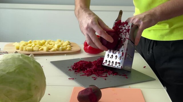 Midsequence kitchen action of person grating beetroot over cutting board with diced potatoes on