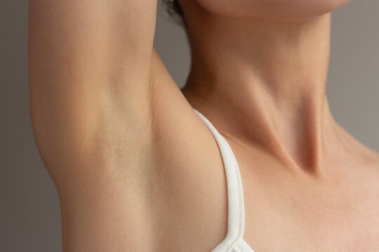 Close-up of young woman showing clean smooth and healthy armpit skin. Concept for hair removal, laser epilation, deodorant advertising, skin care, personal hygiene, and natural body care.