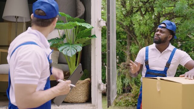 Home moving and delivery service concept. Teamwork of professional home and furniture moving with a truck from business service company. Two male movers in uniforms working and delivering to customer.