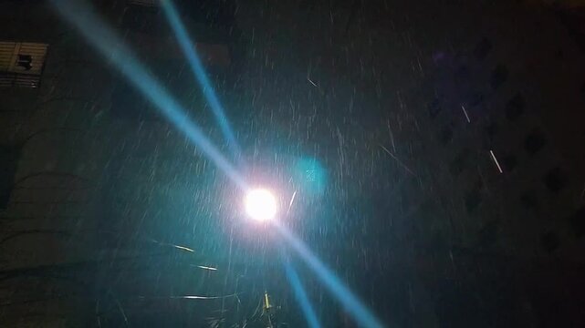 The rain drops in city lights.