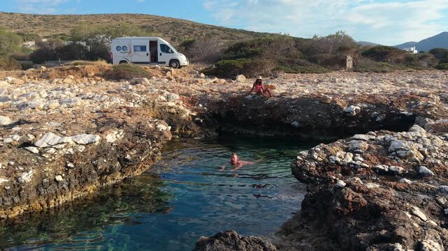 A couple swimming in the ocean of Paros Island in Greece. This serene spot features clear turquoise waters and unique rock formations, perfect for relaxation and holiday adventures.