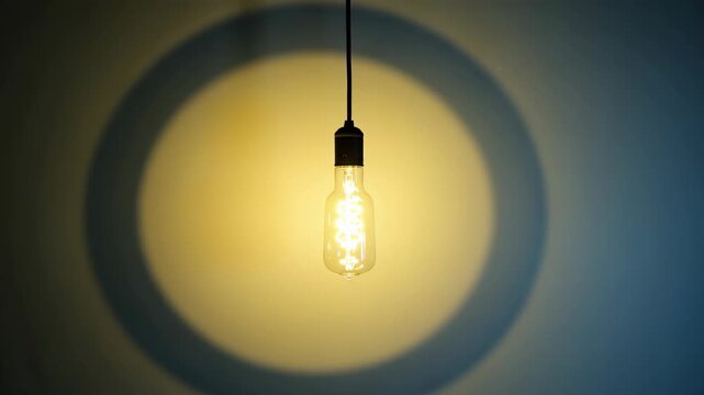 An old-fashioned glass bulb with a glowing filament against a black background.