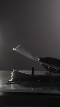 Vertical video hand with dark sleeve inserting a clear plastic sleeve containing a document into a ring binder, symbolizing organization, legal work, or archiving sensitive information